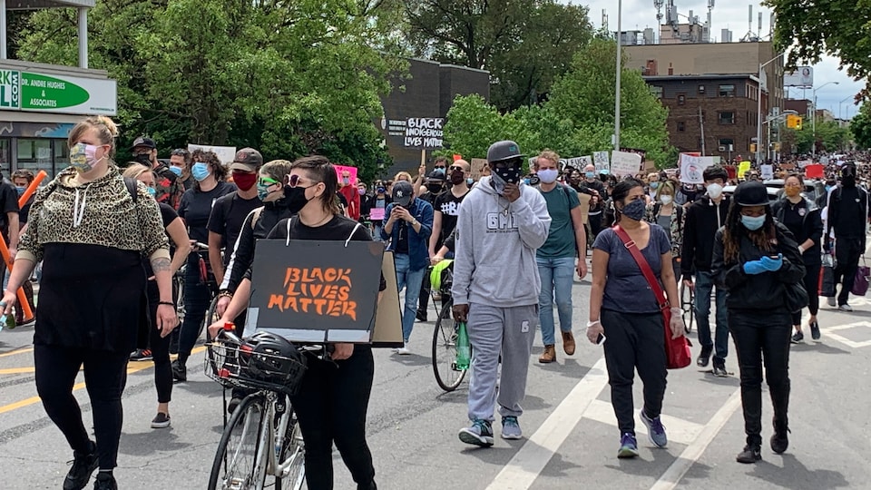 Des manifestants masqués marchent dans une rue de Toronto.