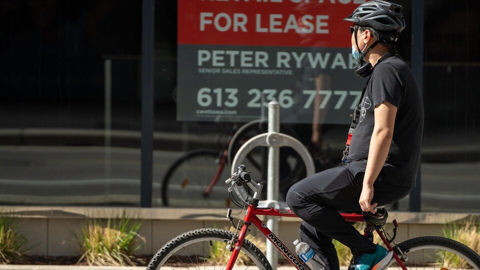 Un homme à vélo au centre-ville d'Ottawa porte un masque.