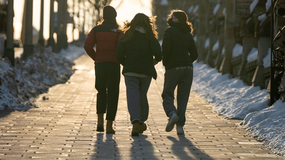 Trois amis marchent à Ottawa en hiver.
