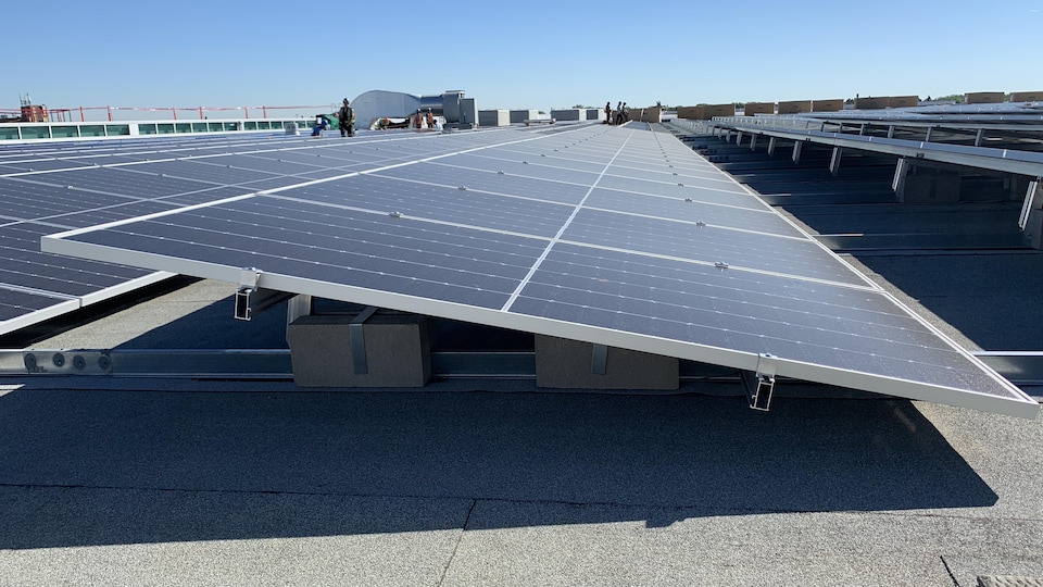 Des panneaux solaires noirs montés sur une structure métallique argentée sur un toit en béton gris par une journée ensoleillée, le 18 août 2022.