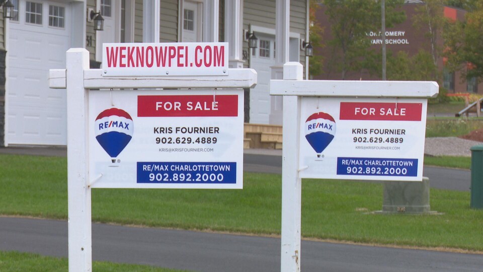 Deux panneaux devant des maisons neuves indiquent qu'elles sont à vendre.