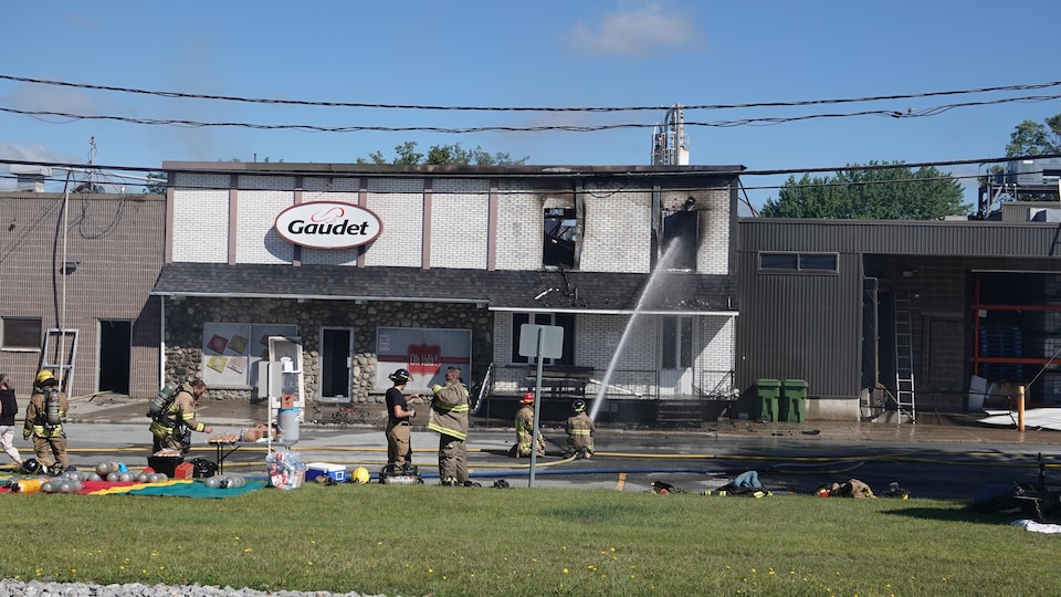 Des pompiers arrosent le bâtiment de la Pâtisserie Gaudet.