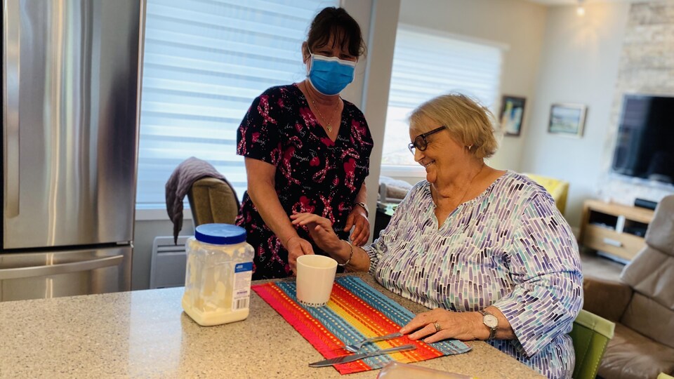 La préposée sert un thé à la dame de 86 ans.