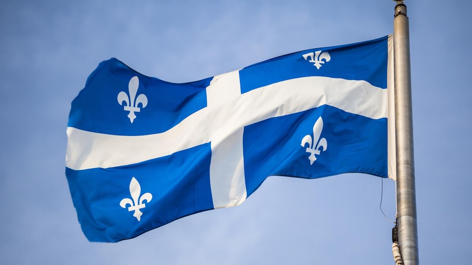 Le drapeau du Québec qui flotte au vent sur un mât.