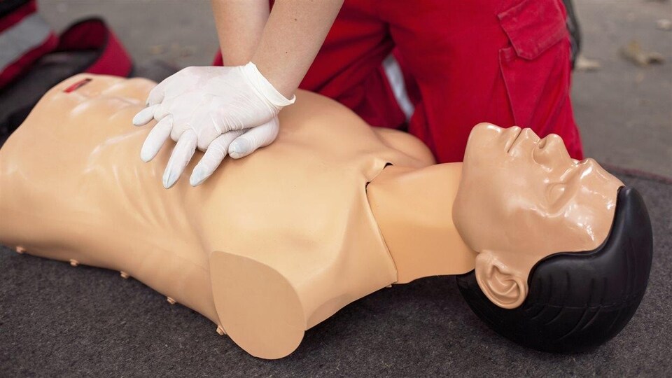 Une personne qui porte des gants pratique la RCR sur un mannequin.