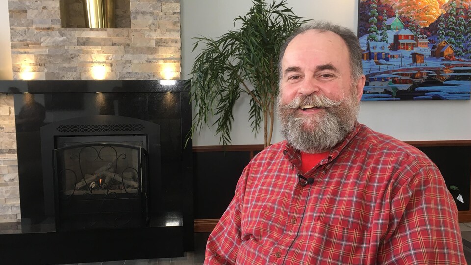 L'homme dans la cinquantaine prend la pose devant un foyer avec sa moustache et sa barbe bien soignée