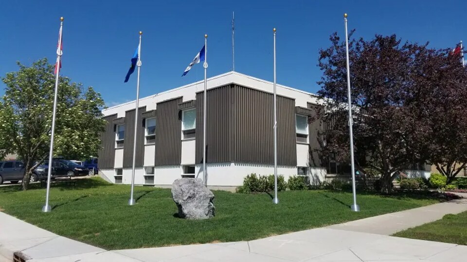 Des drapeaux sont hissés devant un édifice municipal.