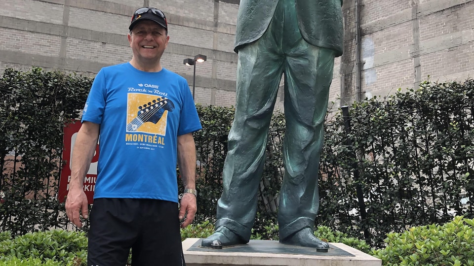 Homme en habits sportifs souriant à côté d'une statue.