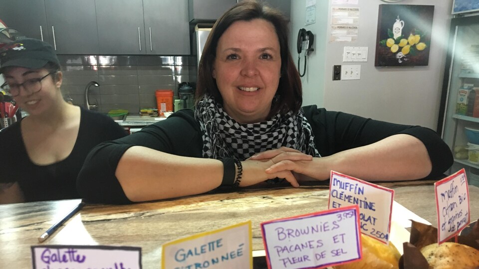 Une femme dans un restaurant devant des muffins et brownies.