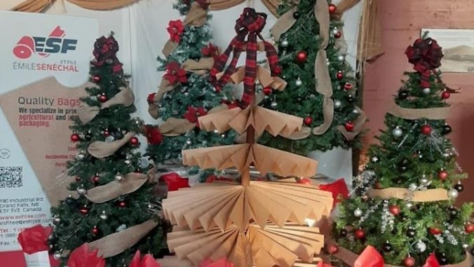 Des sacs de pommes de terre entourent cinq sapins de Noël décorés. Celui du milieu est fait à partir de papiers pliés en accordéon.
