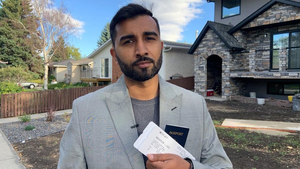 Safwan Choudhry tient un billet d'avion dans ses mains dans une rue résidentielle.