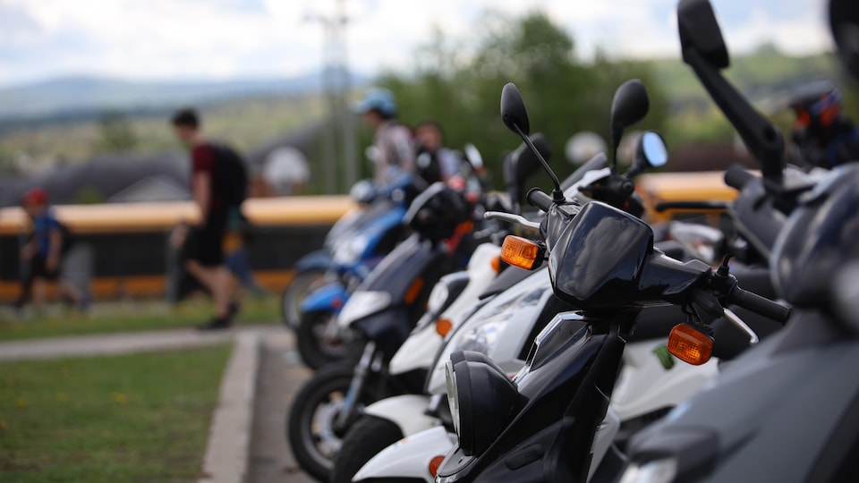 De nombreux scooters stationnés dans une cour d'école. 