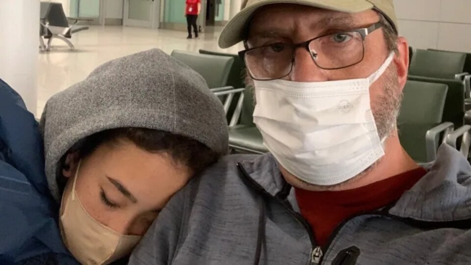 Un père et sa fille assis dans une salle d'attente d'aéroport.