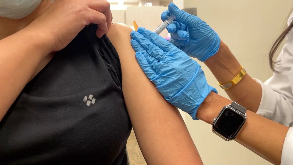 La pharmacienne Shivali Sharma inocule un vaccin contre la grippe à une cliente dans l'un de ses magasins Shoppers Drug Mart à Edmonton.
