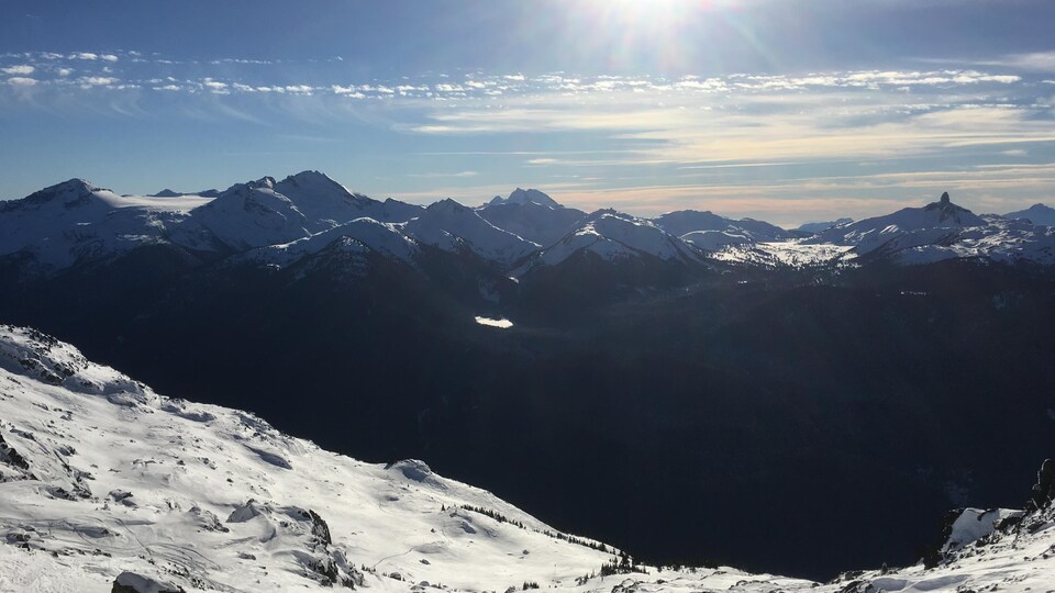 Sommet d'une montagne au soleil avec de la neige et une autre chaîne de montagnes à l'arrière-plan
