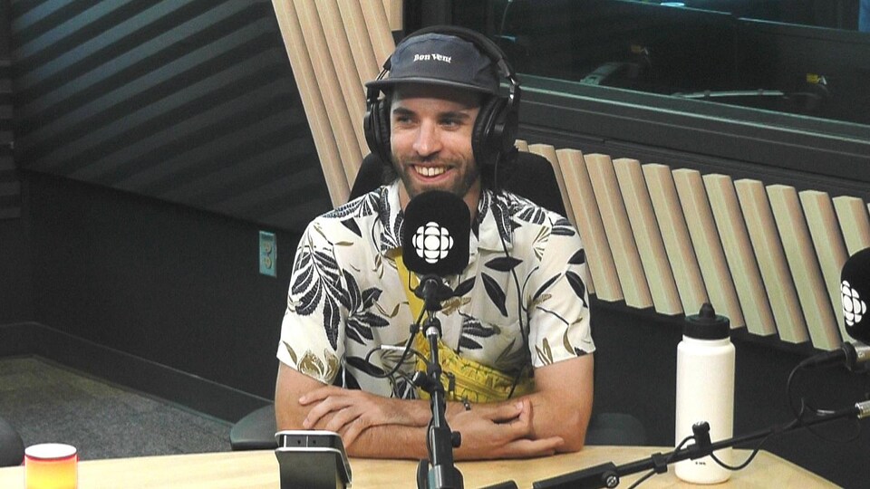 Un homme souriant en entrevue dans un studio de radio.