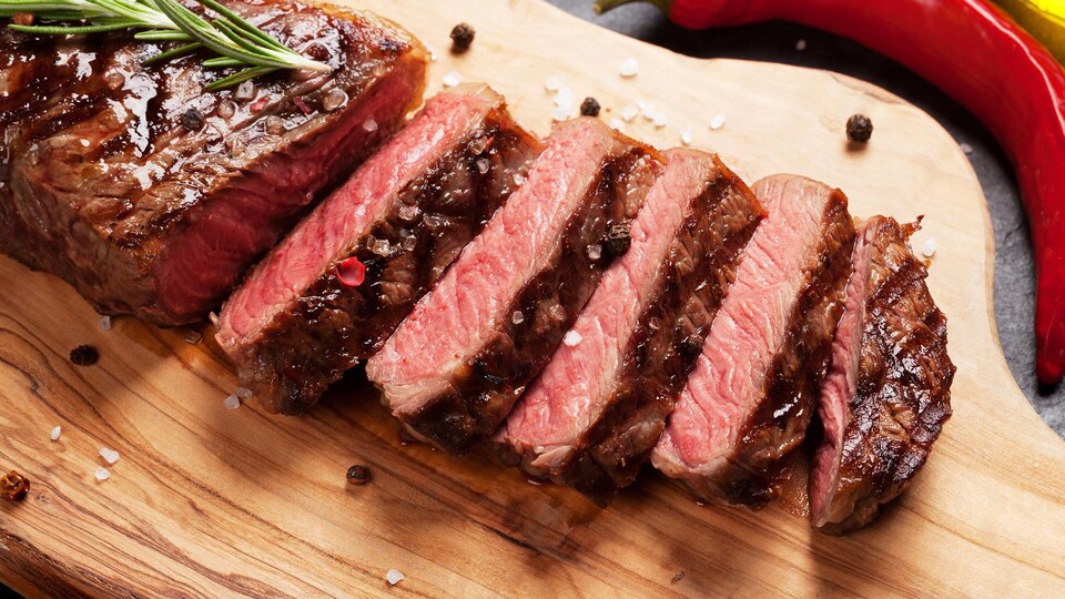Gros plan d'un steak coupé en morceaux sur une planche de bois.