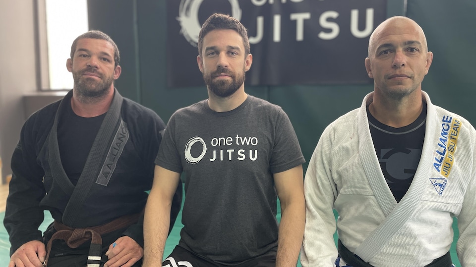 Trois hommes amateurs de jiu-jitsu sourient à la caméra. 