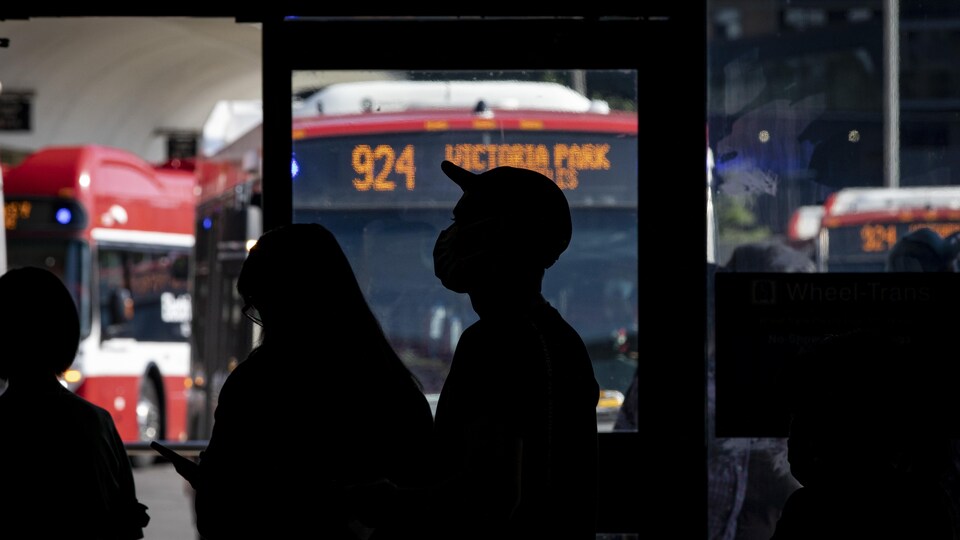 Des ombres de personnes masquées devant une fenêtre à travers laquelle  on aperçoit un autobus de la CTT.