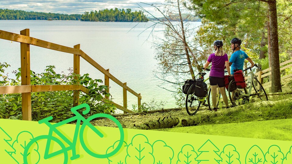 Un couple debout à côté de leurs bicyclettes en train de regarder un lac et ses environs.