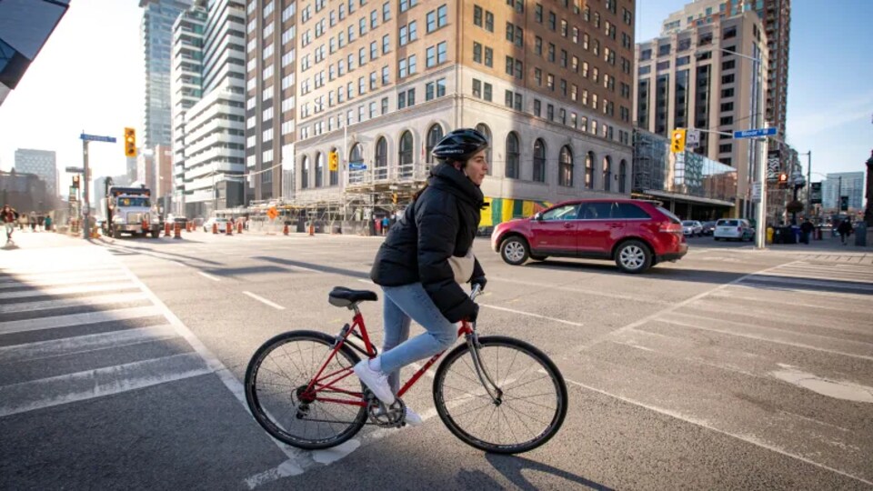 Une cycliste tourne à une intersection en milieu urbain.