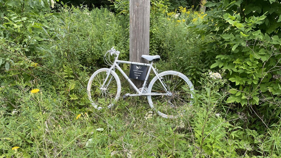 Un vélo peint en blanc sur lequel il est écrit "Une cycliste est décédée ici. Estelle Leblanc. 9 octobre 2021".