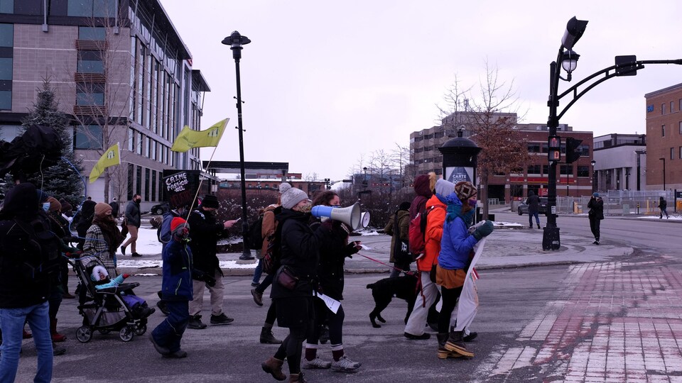 Des manifestants marchent dans Sherbrooke. Une femme tient un porte-voix. 