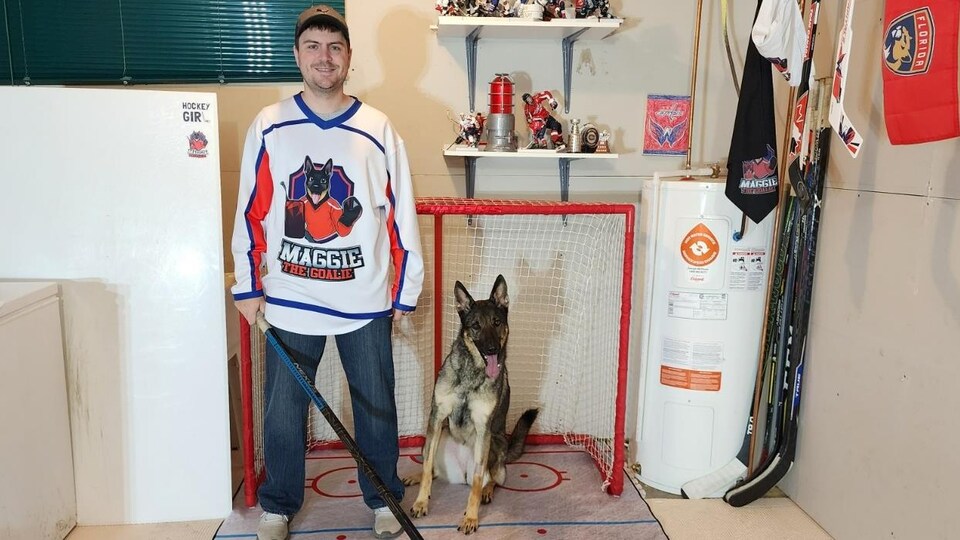 Yannick Devost devant un filet de hockey avec son chien.