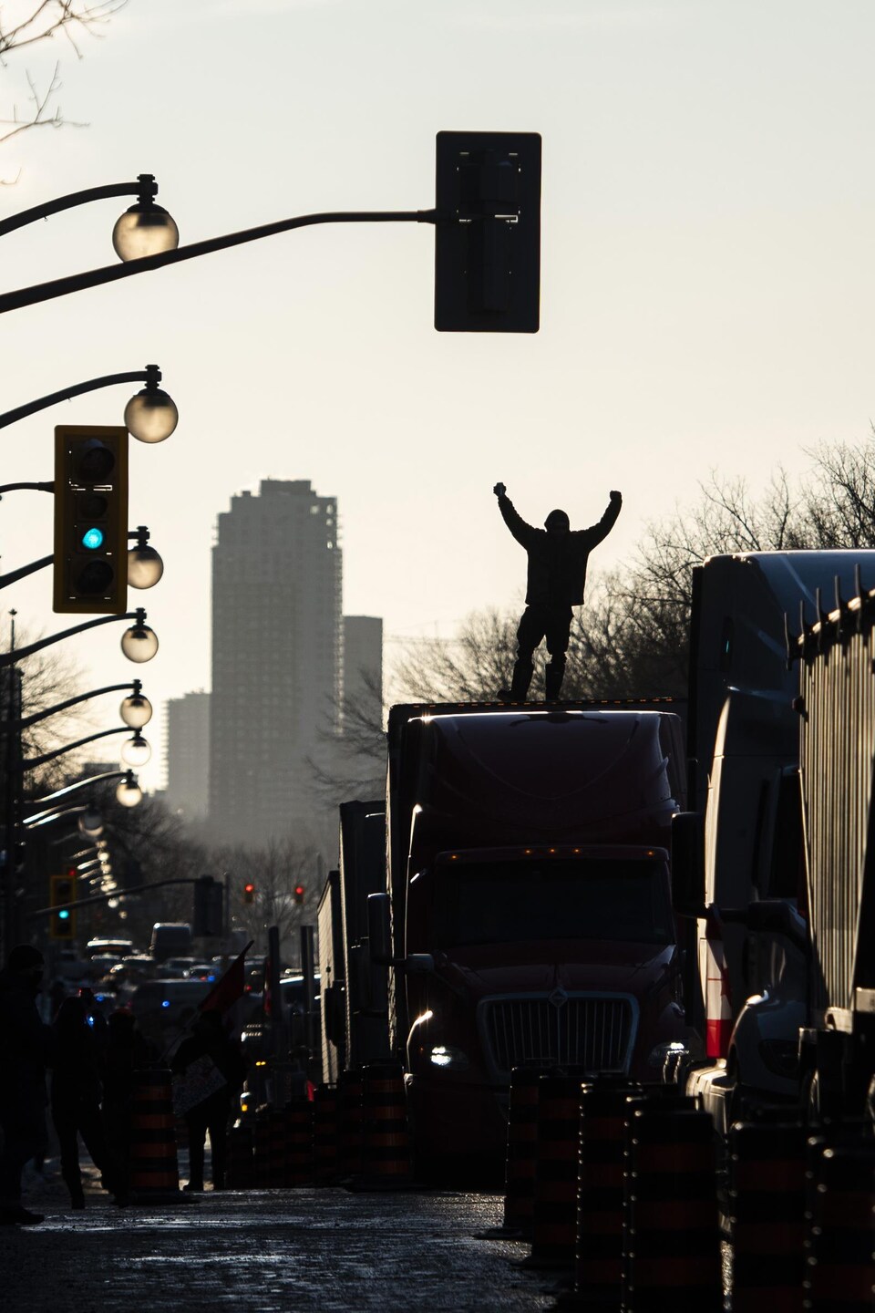 Un manifestant debout sur un camion stationné au coucher de soleil.