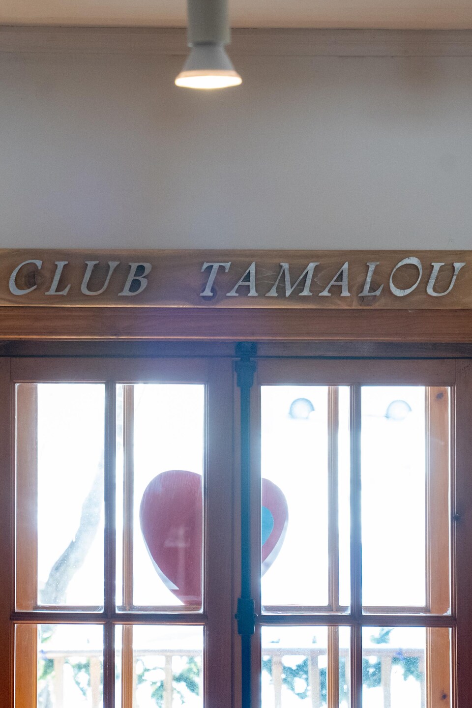 Une fenêtre avec une planche de bois au-dessus sur laquelle il est inscrit : Club Tamalou.