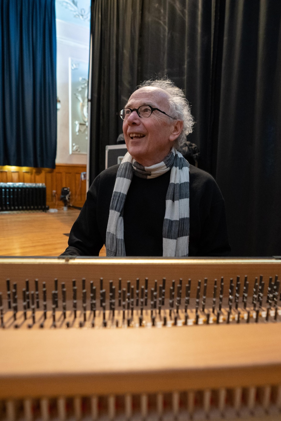 Un homme derrière un orgue dont le couvercle a été ouvert. Il regarde au loin et sourit. 