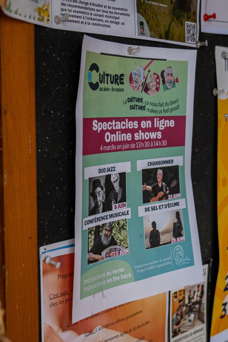 Un babillard rempli d'affiches dont une où est inscrit la programmation des spectacles en ligne offert par Le P'tit bonheur de Saint-Camille.