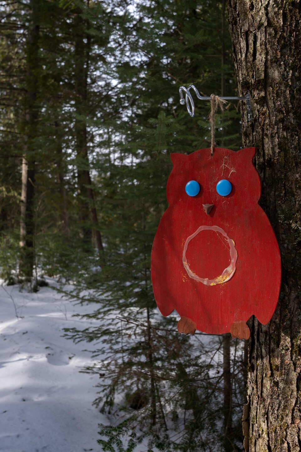 Un hibou découpé dans du métal accroché à un arbre.