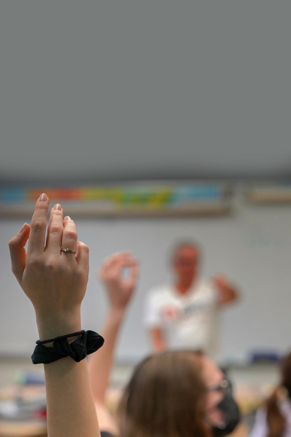 Des mains levées d'élèves dans une classe du secondaire.