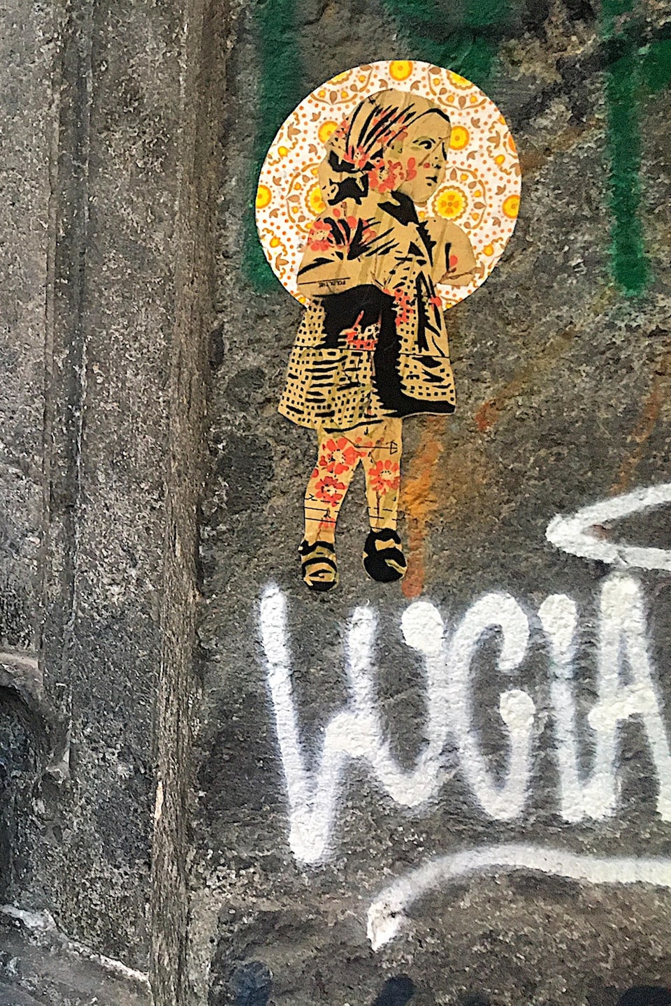 Une œuvre qui représente un enfant est collée sur un mur à côté d'une statue.