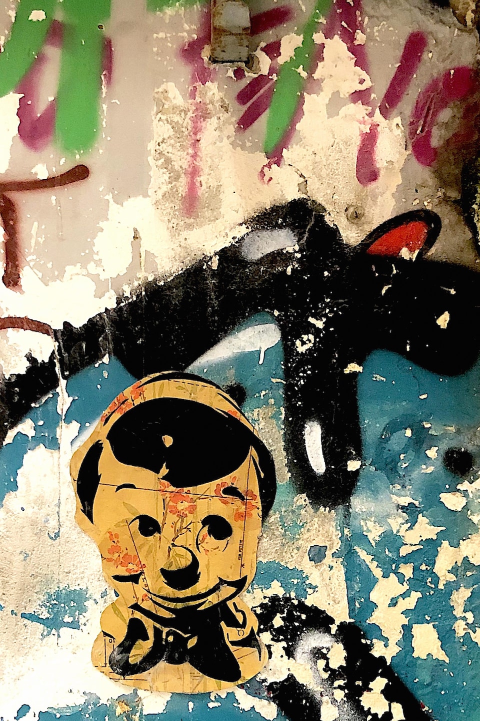 Une œuvre qui représente le personnage de Pinocchio est collée sur un mur.