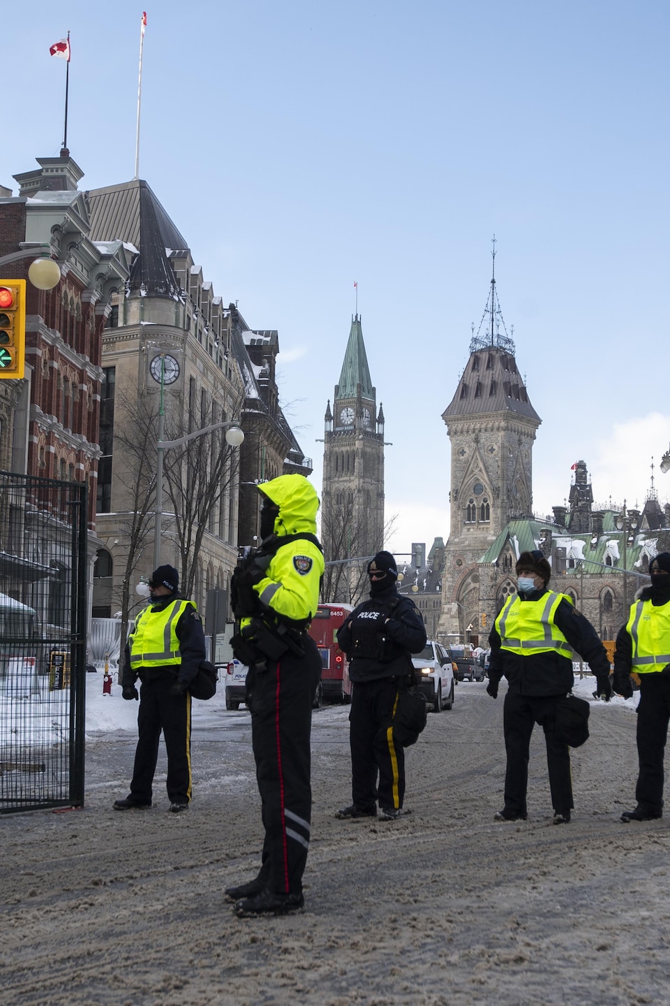 La tour de la Paix est vue derrière la police le long de la rue Queen, alors qu'ils restreignent l'accès aux rues autour de la colline du Parlement pour mettre fin à la manifestation des camionneurs à Ottawa, le samedi 19 février 2022.
