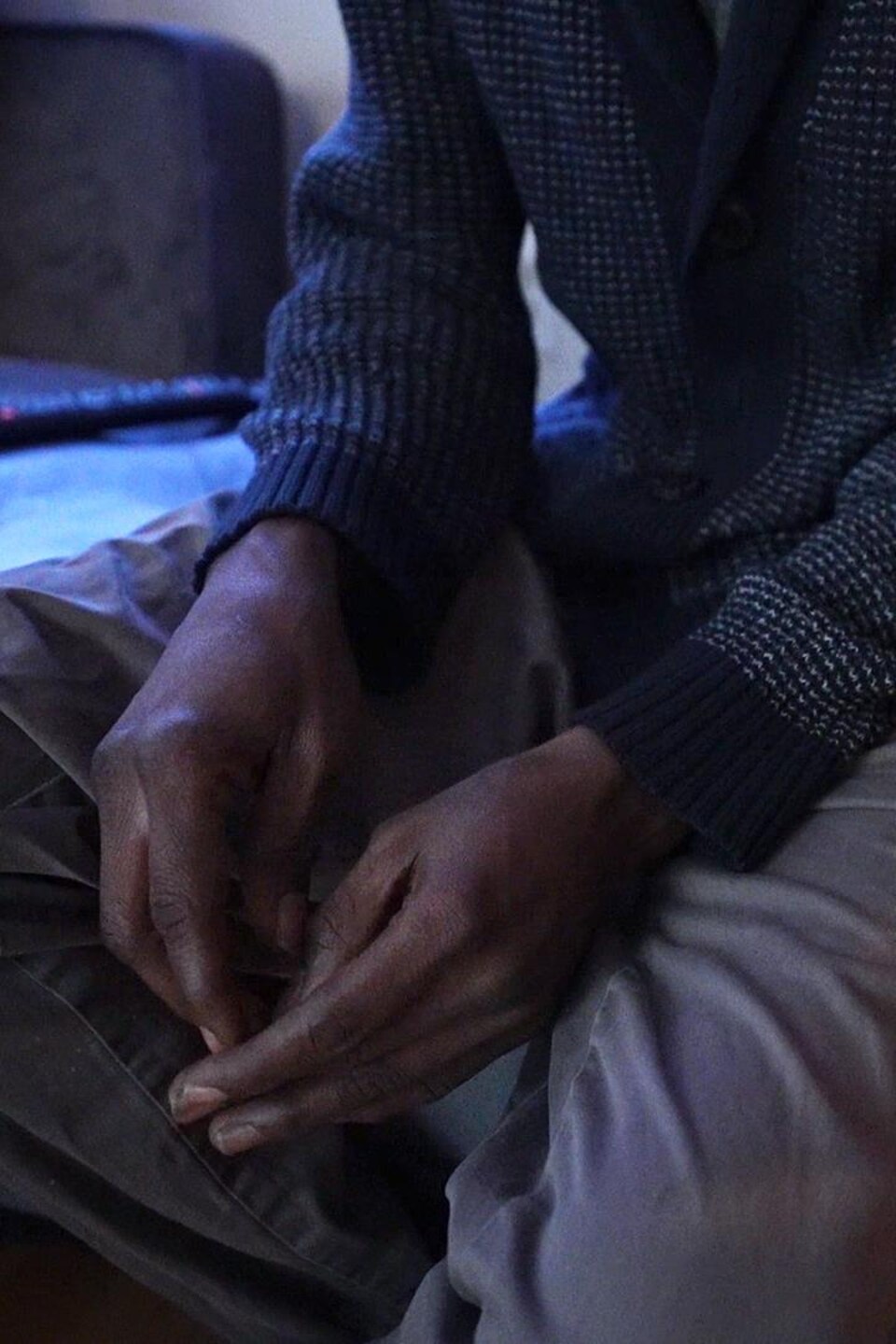 Les mains d'un homme assis sur un canapé.