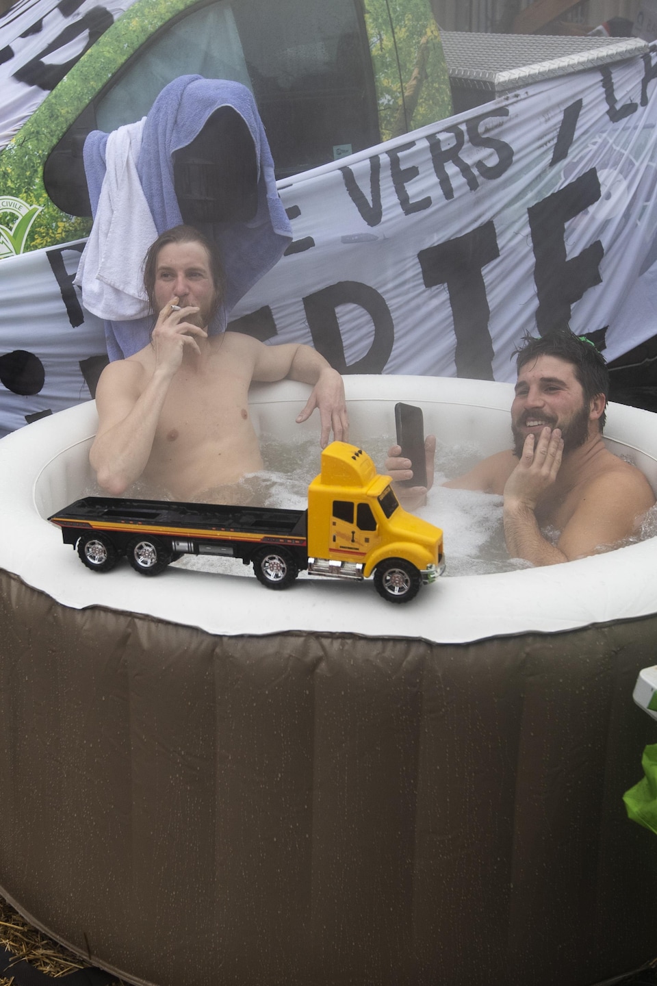 Un camion-jouet est en équilibre sur le bord d'un bain à remous gonflable dans lequel se baignent des manifestants à côté d'une camionnette à Ottawa, le jeudi 17 février 2022.