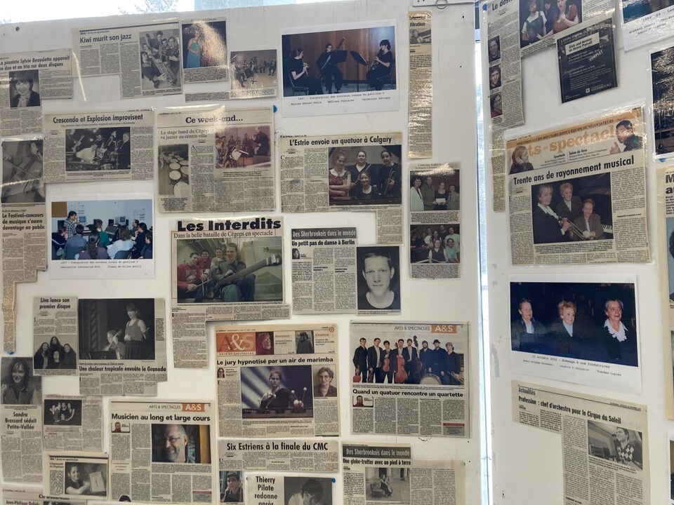 Une affiche sur laquelle sont collés différents articles de journaux. 