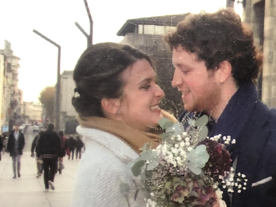 Photo de couple de Claudia Gilbert-Baron et de Kevin Reda Grinsnir. Elle tient des fleurs et ils se regardent amoureusement. 
