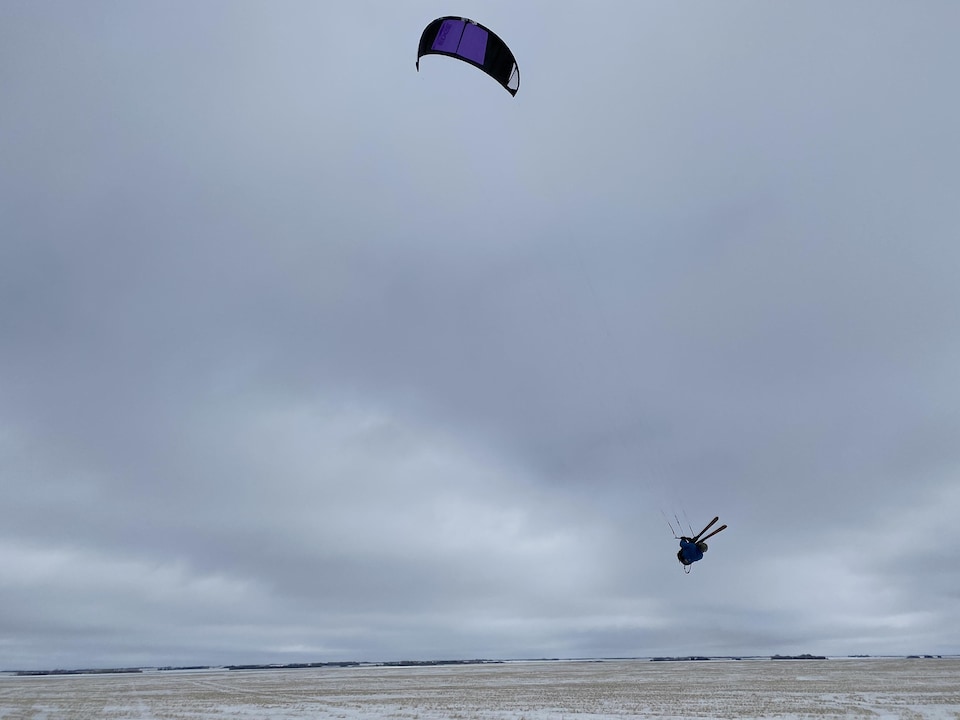 Un adepte de kite sur neige ne touche plus le sol avec ses skis.