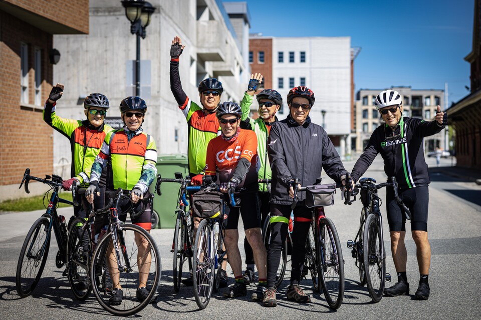 Sept cyclistes a côté de leurs vélos. 