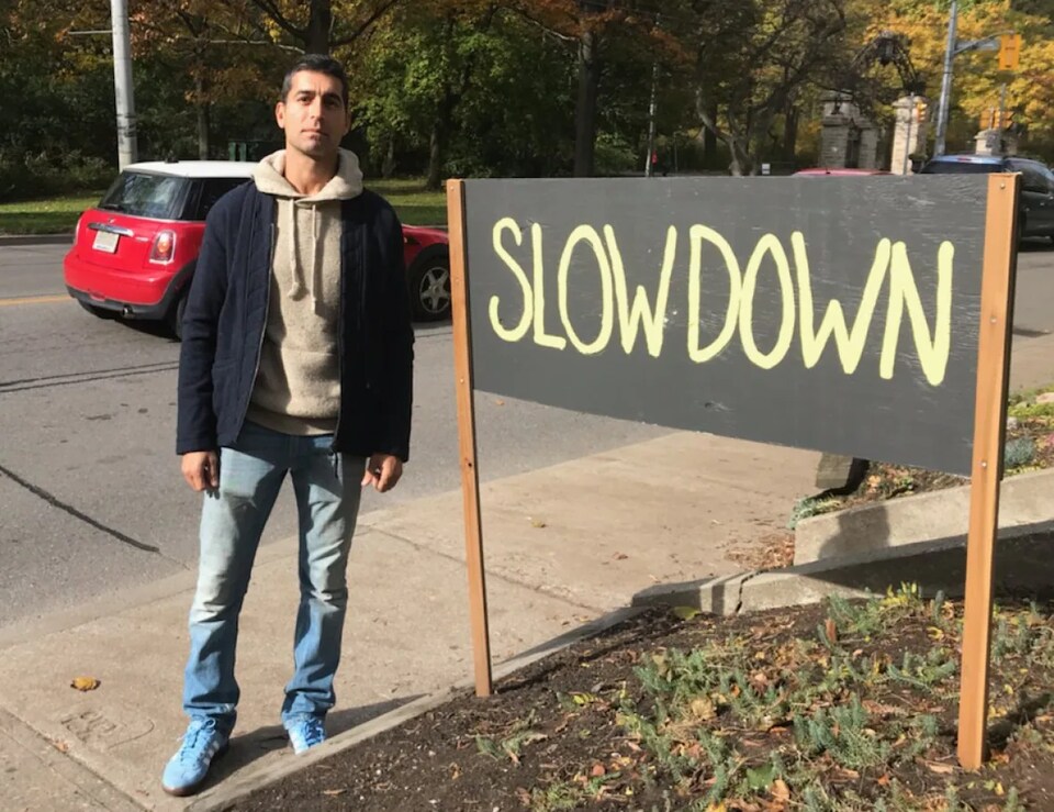 Un homme à côté d'un panneau indiquant de ralentir.