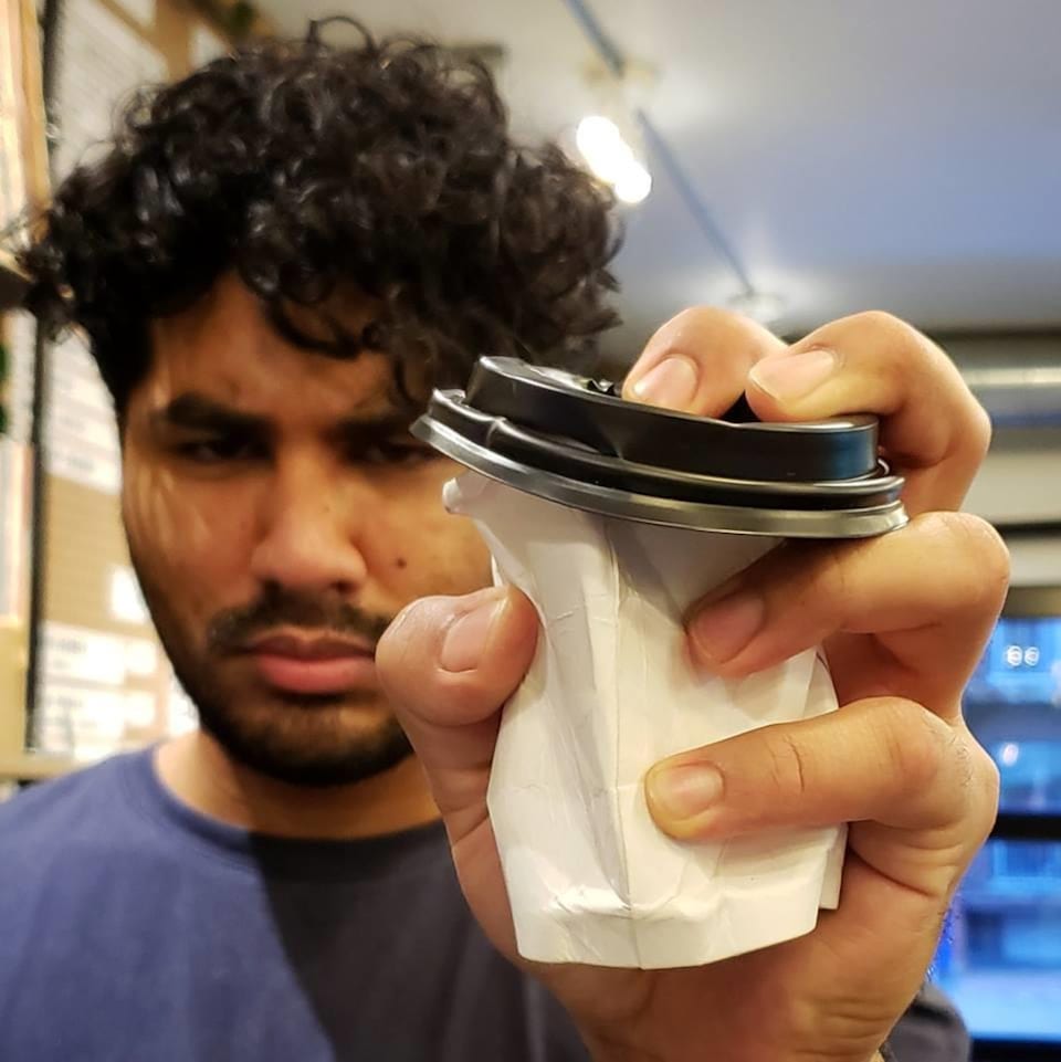 Un homme écrase une tasse de café à usage unique. 
