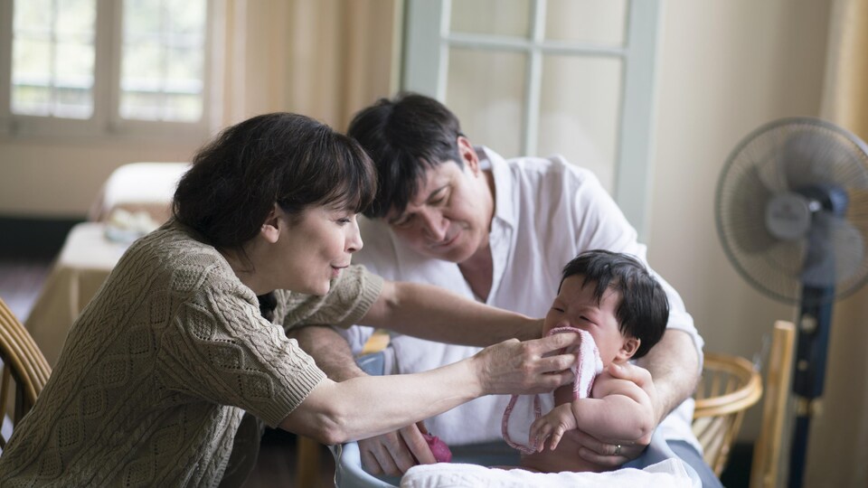 Un couple (Anne Dorval et François Papineau) lavent un bébé.