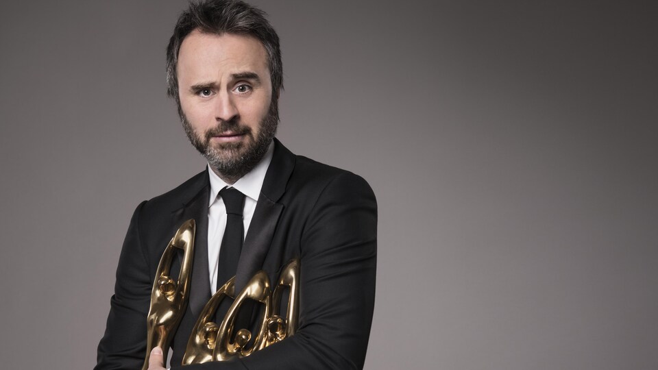 L'animateur tient des trophées Félix dans ses bras.