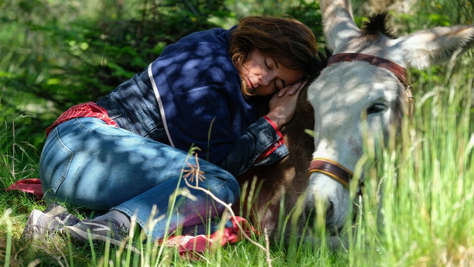 Une jeune femme (Laure Calamy) allongée sur le flanc d'un âne, dans un pré.