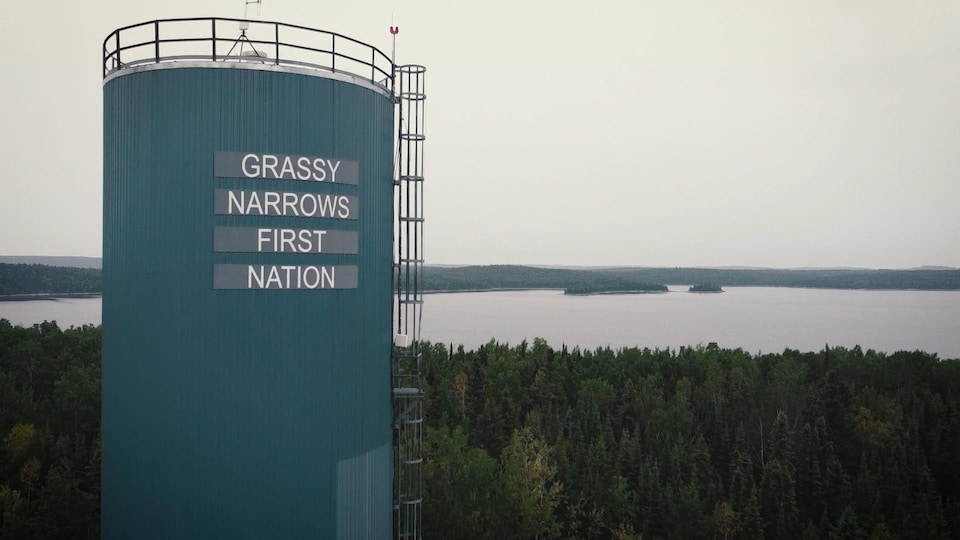 Tour devant une rivière avec inscription anglaise : Grassy Narrows First Nation  