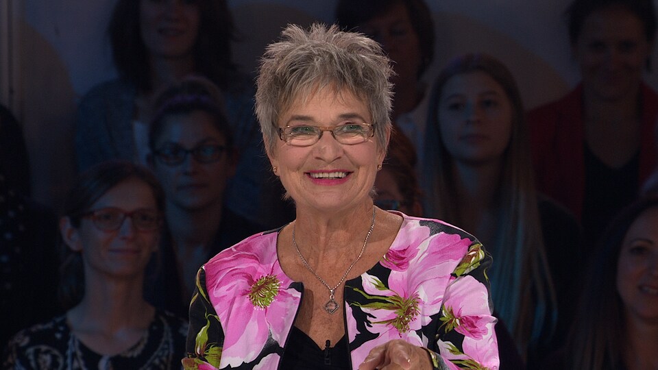 La femme porte une veste à motifs de fleurs sur le plateau des «Enfants de la télé».